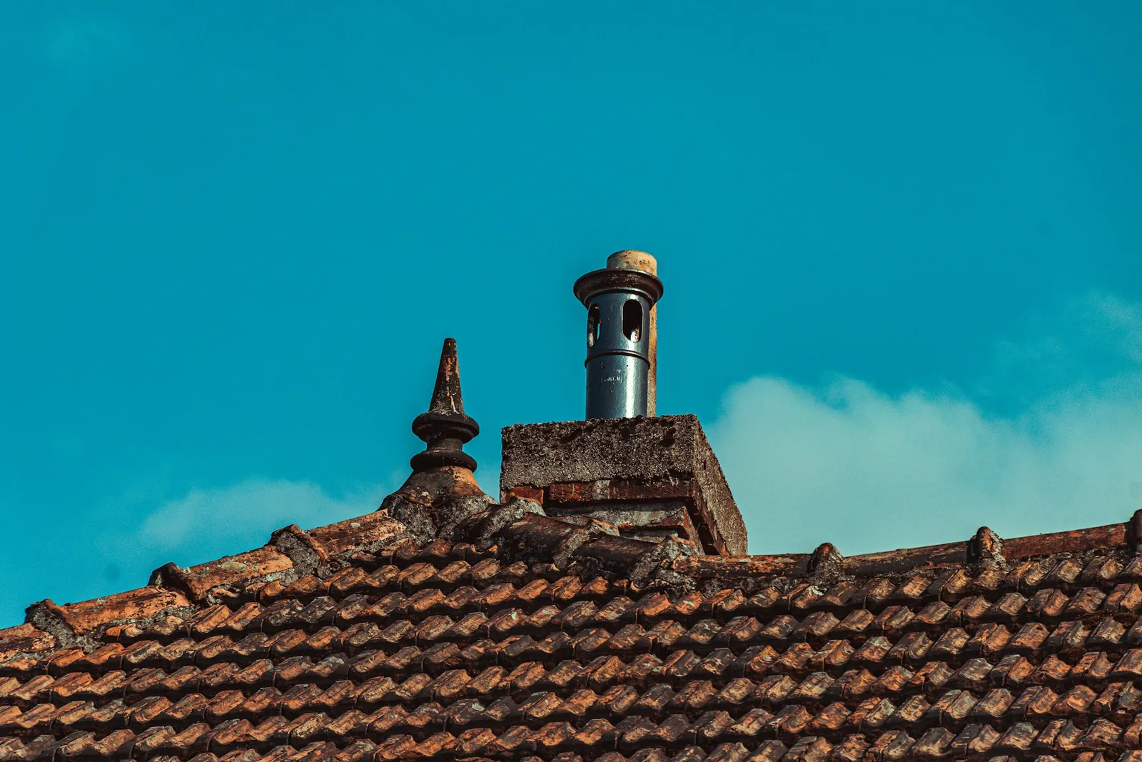 Brick chimney topped with a round metal cap against a blue sky