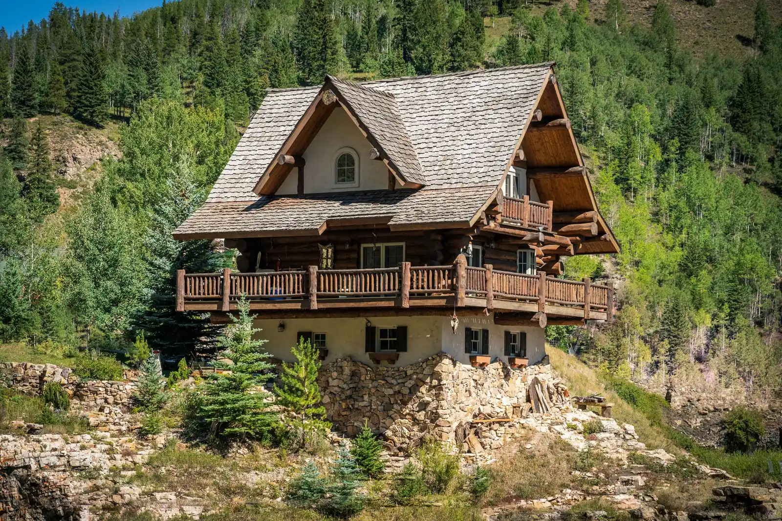 Log and stucco mountain home with wood balconies on a steep forested slope